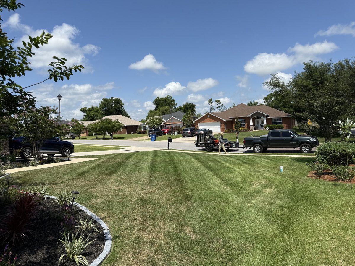 Striped lawn mowing pattern next to a stone-bordered flowerbed in Lynn Haven, FL